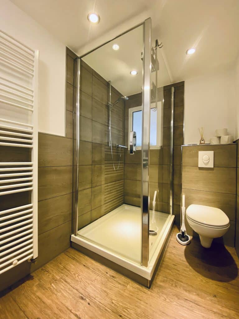 geräumiges Bad mit Dusche, Handtuchheizung, WC und Waschbecken – ideal für Freunde